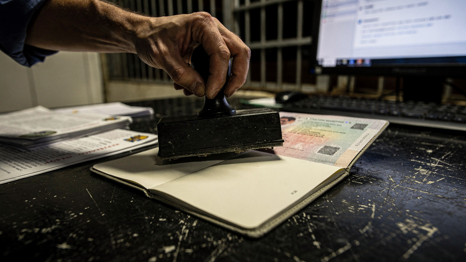 A close-up of a traveler's passport receiving an entry stamp from an official's hand at a Cote d'Ivoire border crossing point.