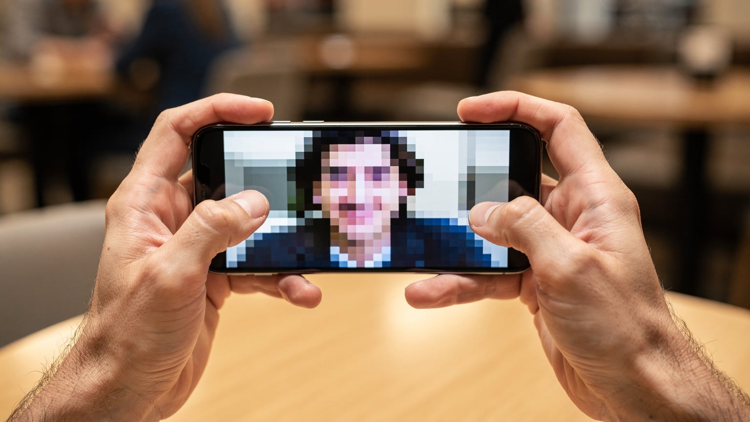 A person holds their smartphone, displaying a blurry, frozen video call screen, illustrating the frustration of attempting video communication on a slow 256kbps connection.