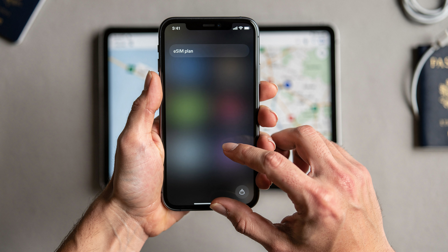 A close-up of a traveler's hands navigating an eSIM plan selection menu on a smartphone, with a blurred digital map in the background.