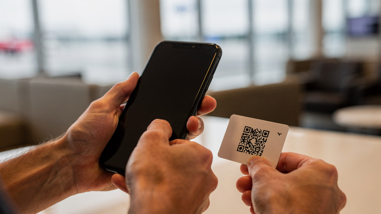 A traveler scans an eSIM QR code on a provided card with her smartphone at a quiet airport lounge, showing focus and ease of activation.