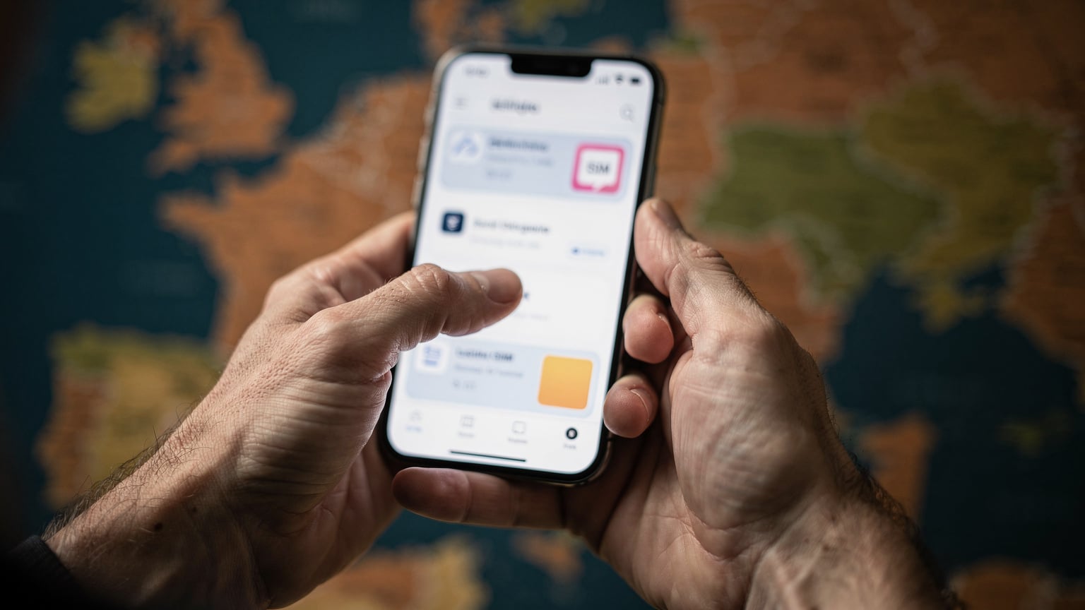 A close-up of a traveler's hands scrolling through various eSIM plan options on their smartphone, with a blurred map of Europe in the background.