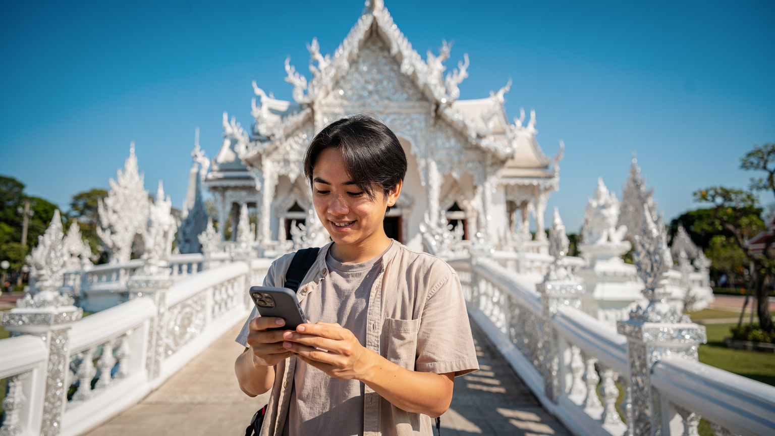 タイのチェンライにあるワット・ロンクン(ホワイト・テンプル)を訪れる日本人旅行者。スマートフォンで観光情報を確認中。