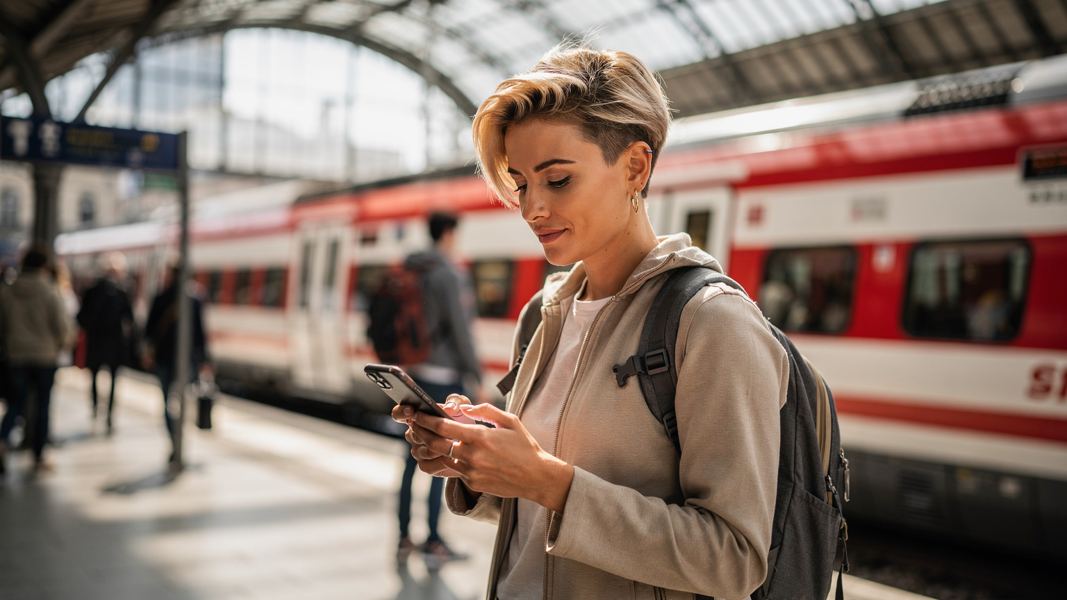 Жінка активує eSIM на смартфоні, перебуваючи на жвавій станції S-Bahn у Мюнхені, Німеччина, демонструючи легкість налаштування зв'язку.