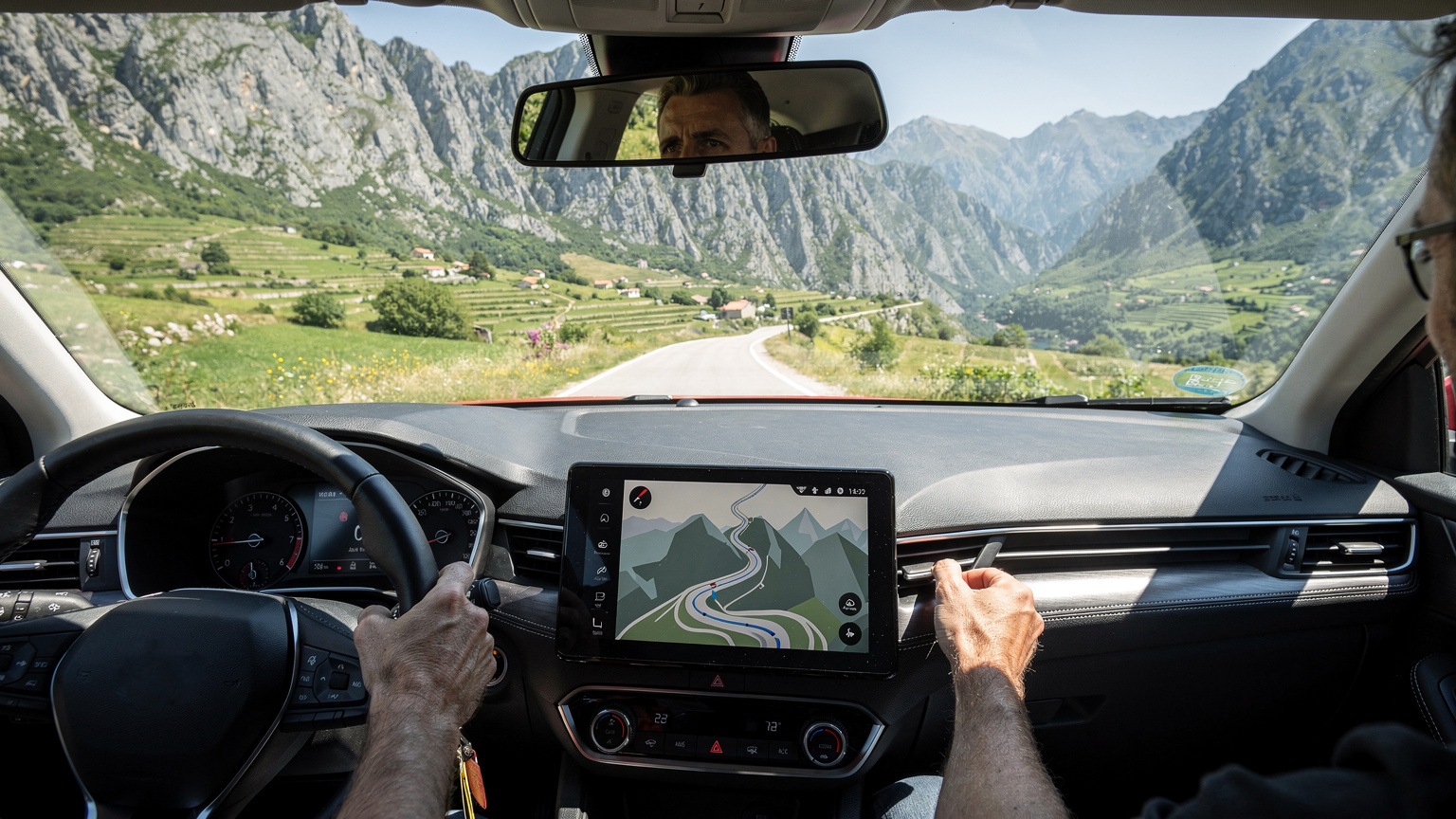 Ein Reisender am Steuer eines Mietwagens auf einer kurvenreichen Landstraße in Montenegro. Das Smartphone mit geöffneter Navigations-App liegt auf dem Armaturenbrett und zeigt eine Route durch eine atemberaubende Berglandschaft mit grünen Tälern und schroffen Gipfeln.