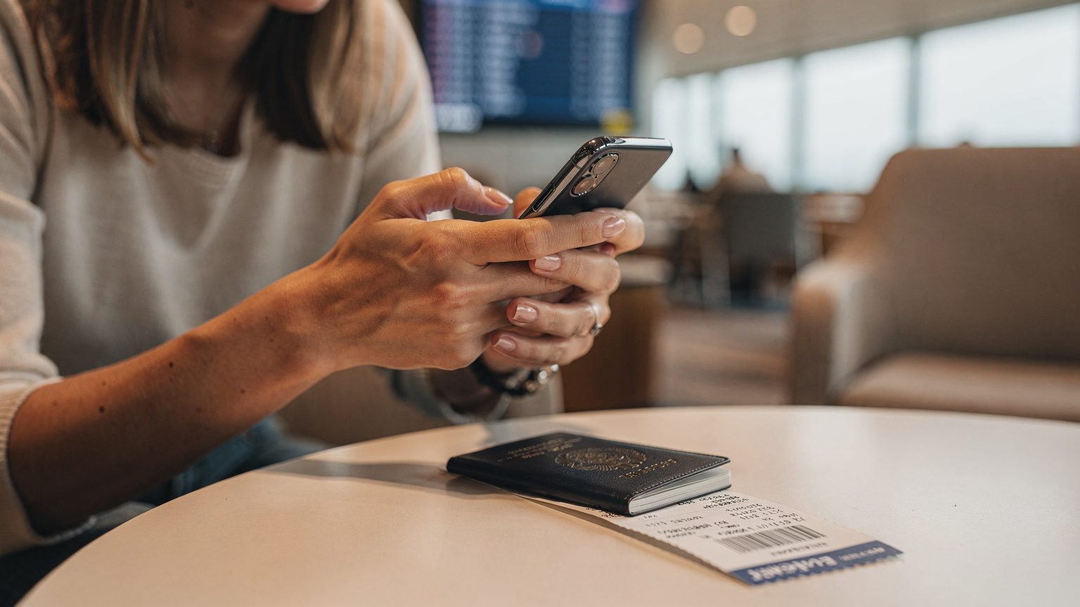 A close-up shot of a traveler's hands, in a well-lit airport lounge in Istanbul, trying to troubleshoot an eSIM issue on their smartphone, with a passport and boarding pass nearby.