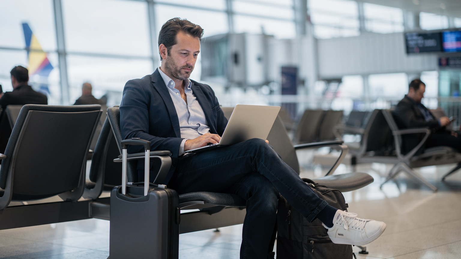 A traveler at an airport gate, checking eSIM plans on a laptop, emphasizing the convenience of digital connectivity before a flight.