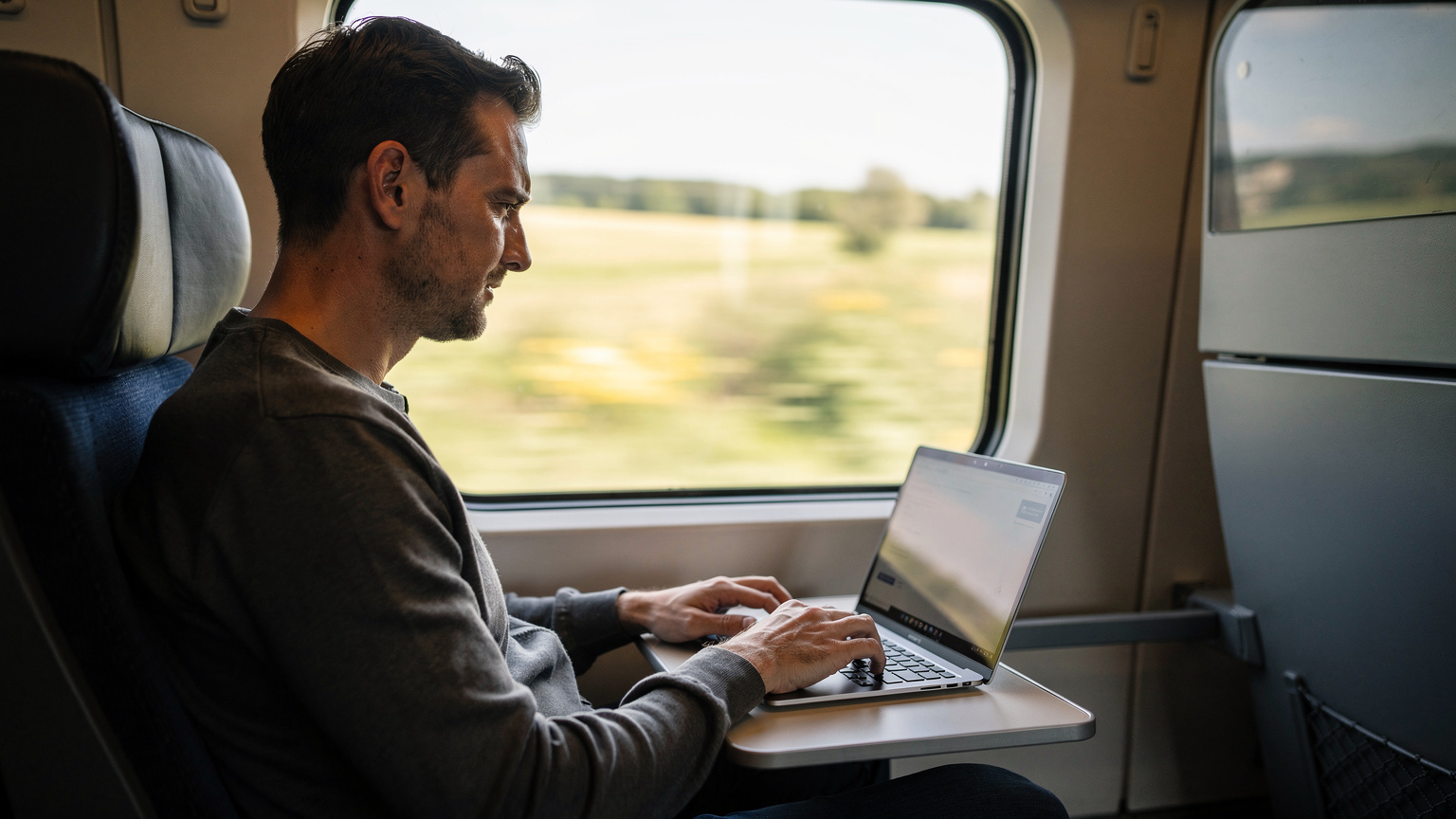 A digital nomad on a train in Europe, using their laptop with an active eSIM, highlighting productivity during transit.