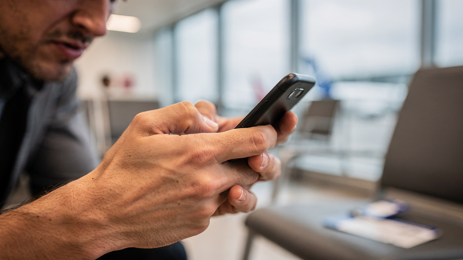A close-up shot of a person's hands holding a smartphone, with a frustrated expression visible on their blurred face in the background, implying connectivity issues.