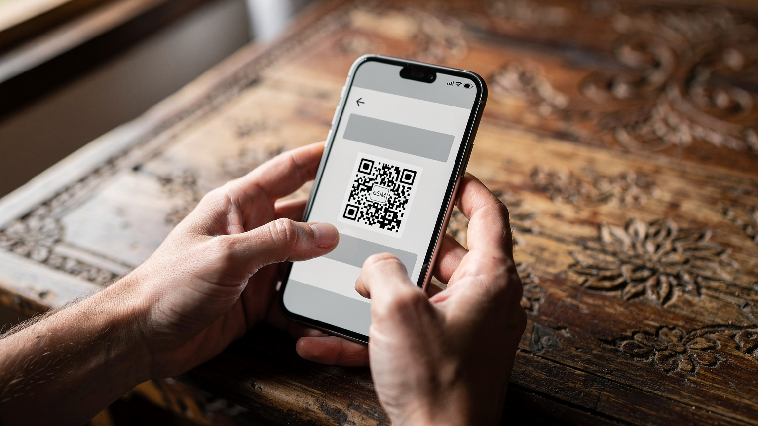 A person's hands delicately hold a smartphone, displaying the eSIM activation QR code on the screen, ready to scan and activate, set against a blurred background of a traditional Bhutanese wooden table.