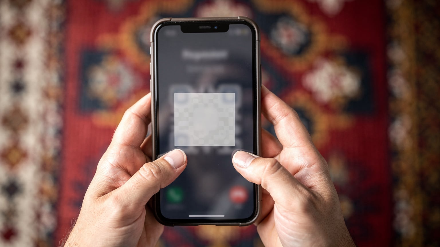 Nærbillede af hænder, der holder en smartphone med en Cellesim eSIM-aktiveringsskærm åben, mod en baggrund af traditionelle albanske motiver.
