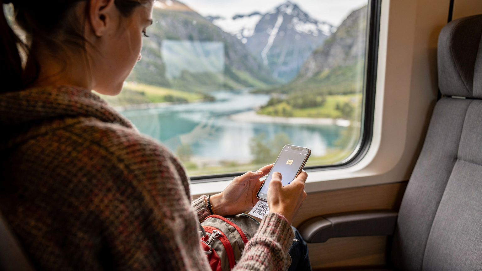 En reisende aktiverer enkelt en eSIM på smarttelefonen sin på et tog som kjører gjennom det norske landskapet, med frodige grønne daler og snødekte fjell i bakgrunnen.