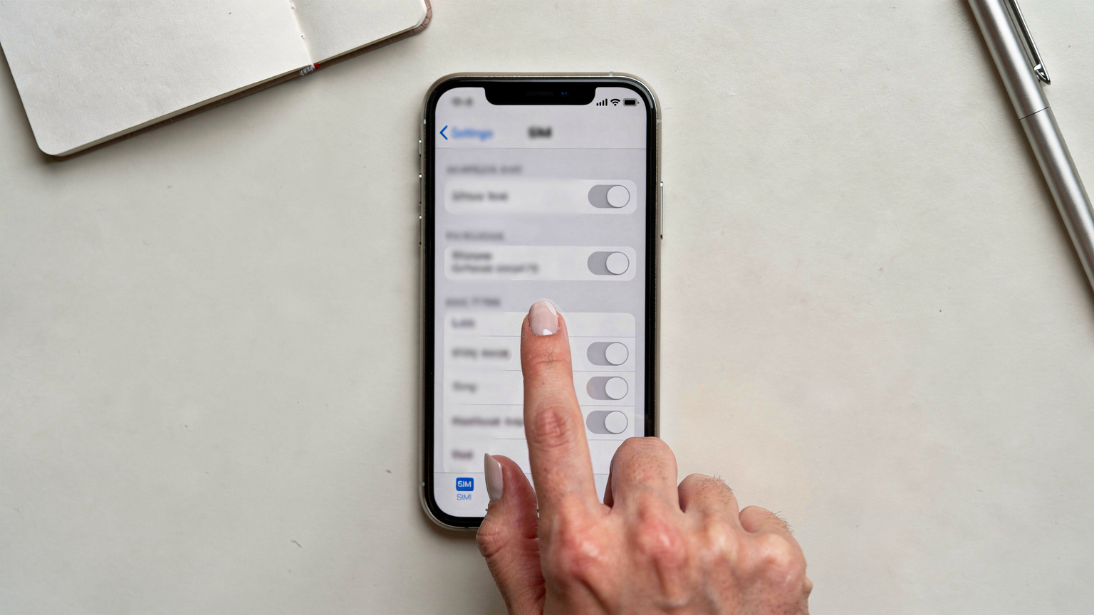一只手正在操作iPhone手机的“设置”界面,屏幕上清晰地显示着“蜂窝网络”或“eSIM”的相关选项,背景是简约的桌面。