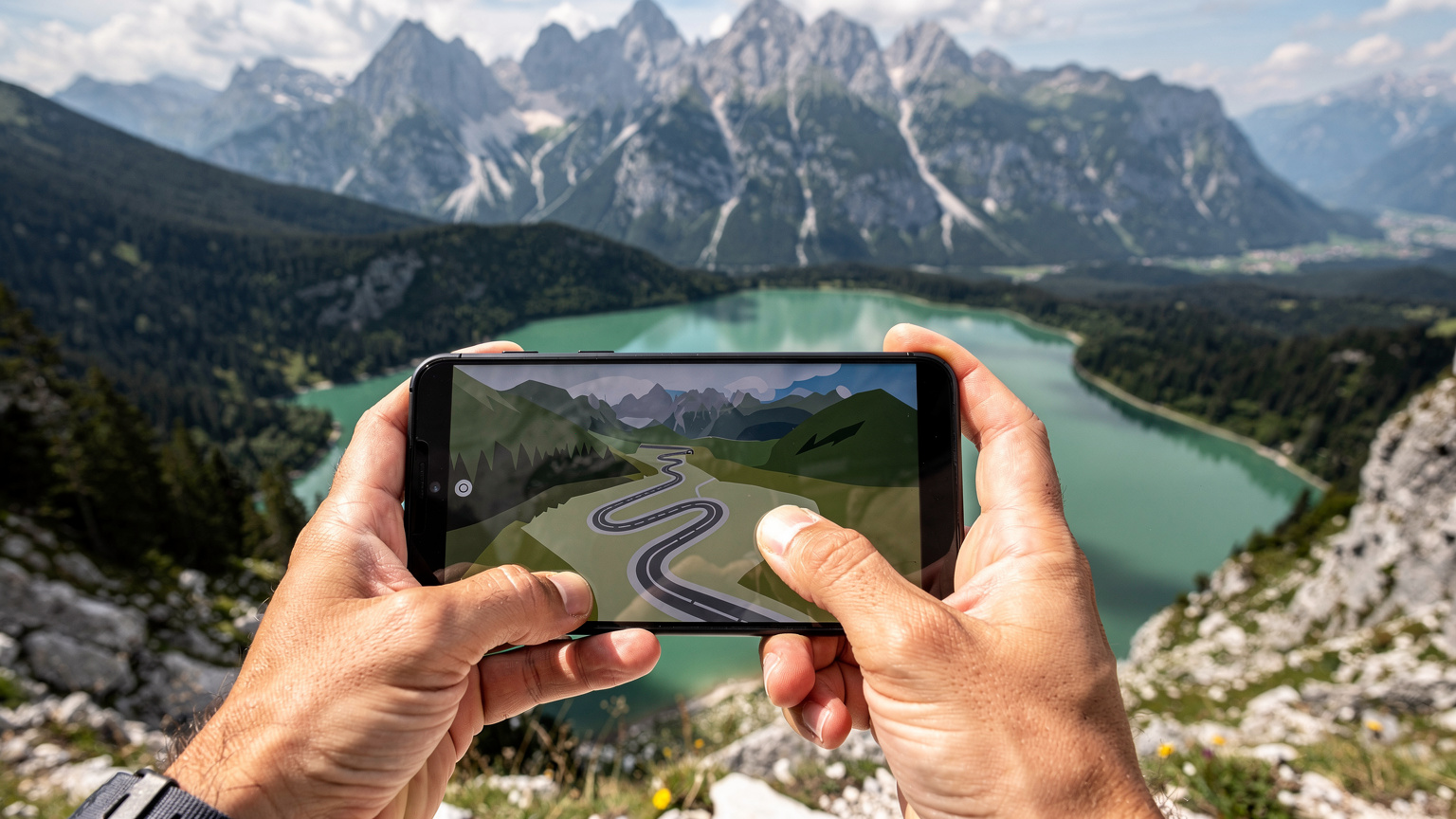 Eine Person hält ein Smartphone in der Hand, auf dem eine Navigations-App mit einer Route durch die Julischen Alpen in Slowenien angezeigt wird, während im Hintergrund ein malerischer Bergsee und grüne Wälder zu sehen sind.