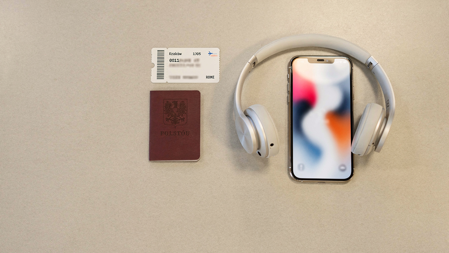 Zbliżenie na paszport, bilet lotniczy i iPhone'a 18 z wyświetloną aplikacją Cellesim, leżące na stoliku lotniskowym.