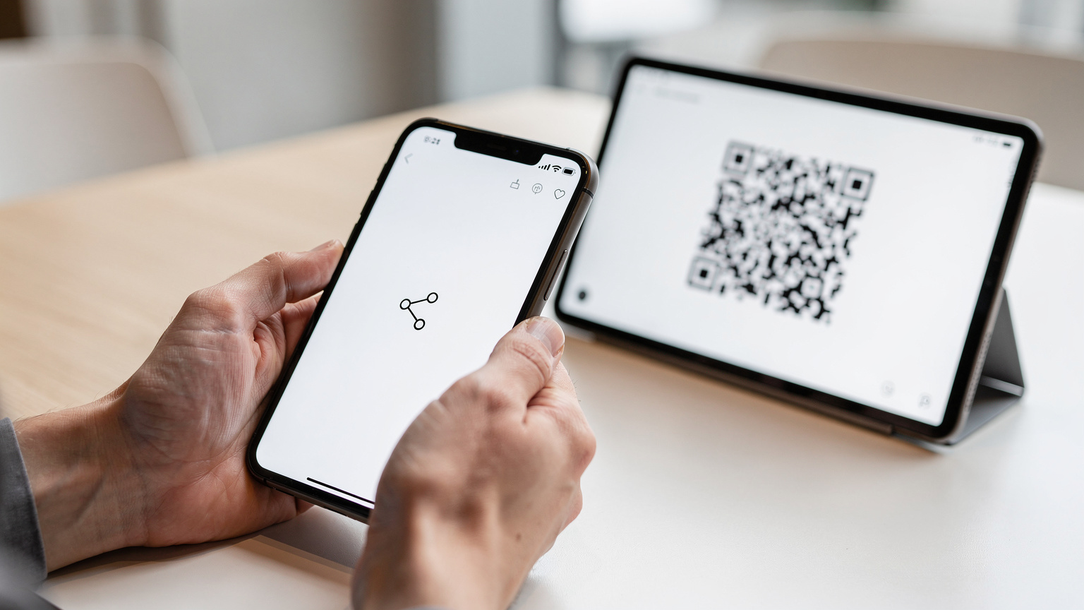 Mânele unei persoane țin un smartphone afișând setările de rețea, în timp ce scanează un cod QR pentru eSIM de pe ecranul unui alt dispozitiv, într-un mediu curat și minimalist.