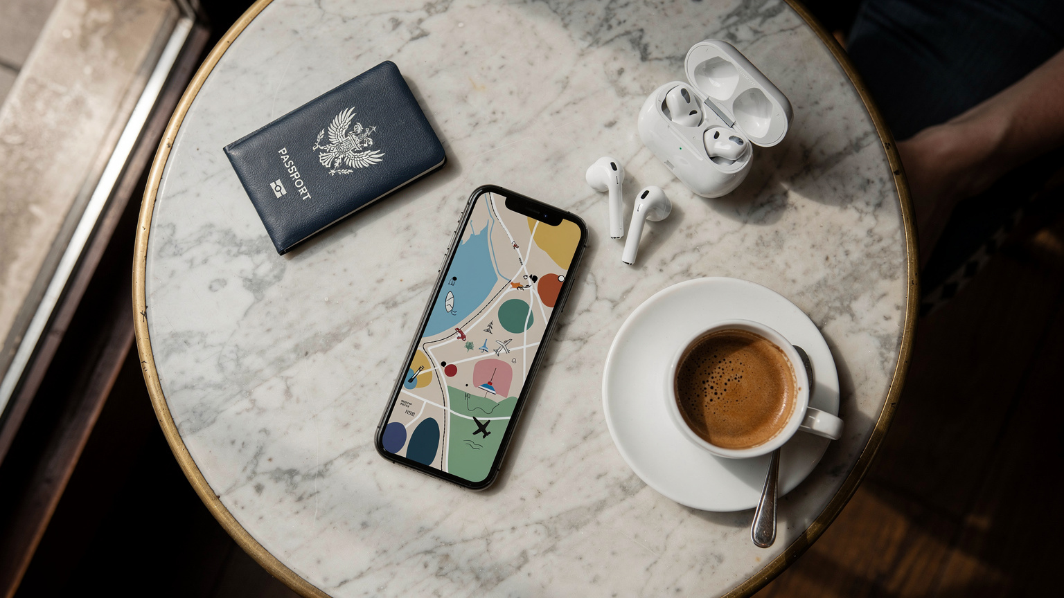 Un passeport, un smartphone avec un écran affichant un plan de voyage, des écouteurs et une tasse de café sur une table de café parisien, illustrant la planification de voyage moderne.
