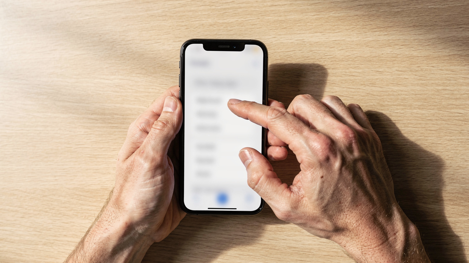 A close-up shot of a person's hands holding a smartphone, with fingers deftly navigating the settings menu, possibly switching between cellular plans, in a well-lit, neutral environment, emphasizing the user's interaction with the device.