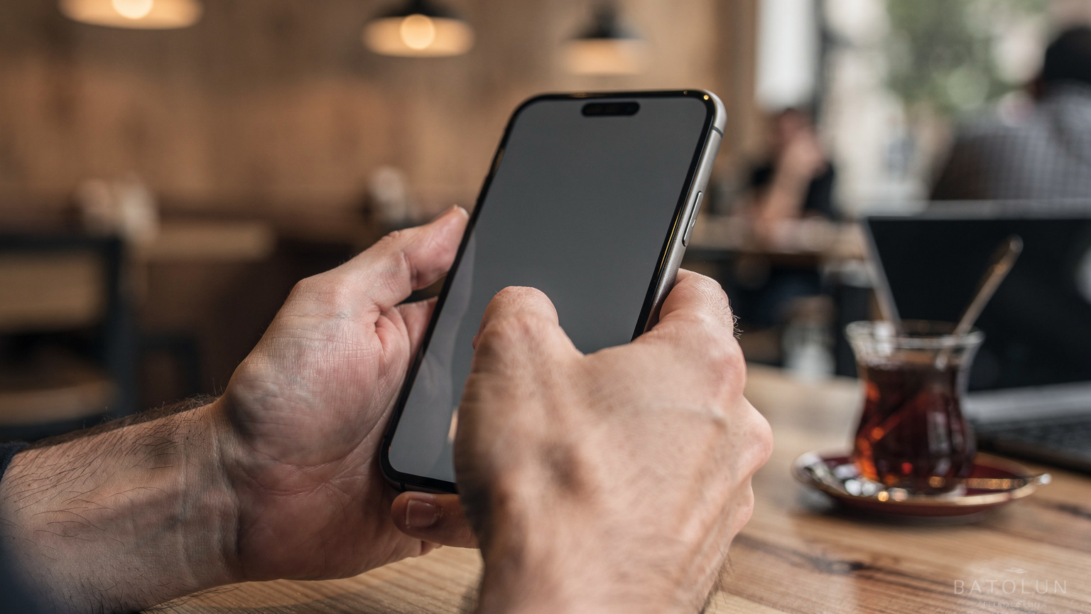 Close-up of a person's hands holding a smartphone, with one thumb hovering over a digital 'Confirm' button on the screen, indicating an eSIM activation step.