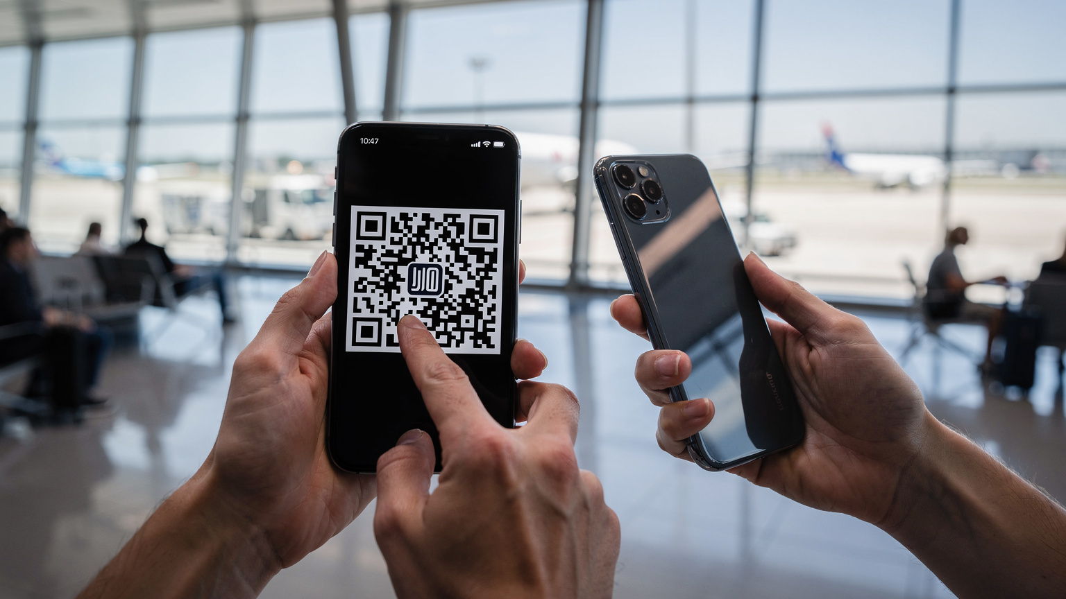 A traveler scanning a QR code on their smartphone at a busy airport terminal, with luggage nearby, suggesting easy eSIM activation before departure.