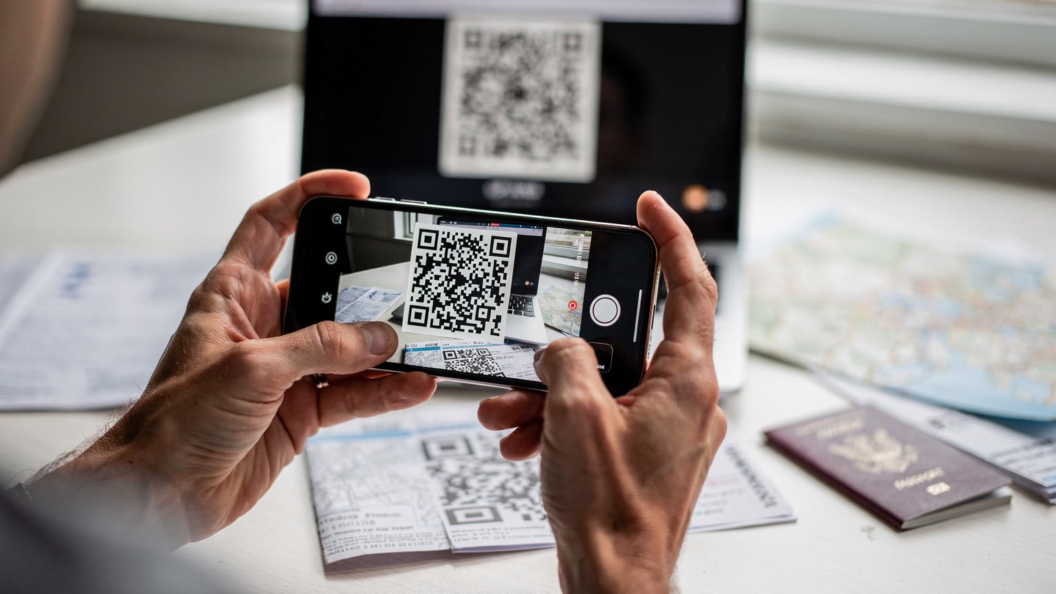 A close-up of a parent's hands holding a smartphone, scanning a QR code for eSIM activation, with a blurred travel itinerary in the background.