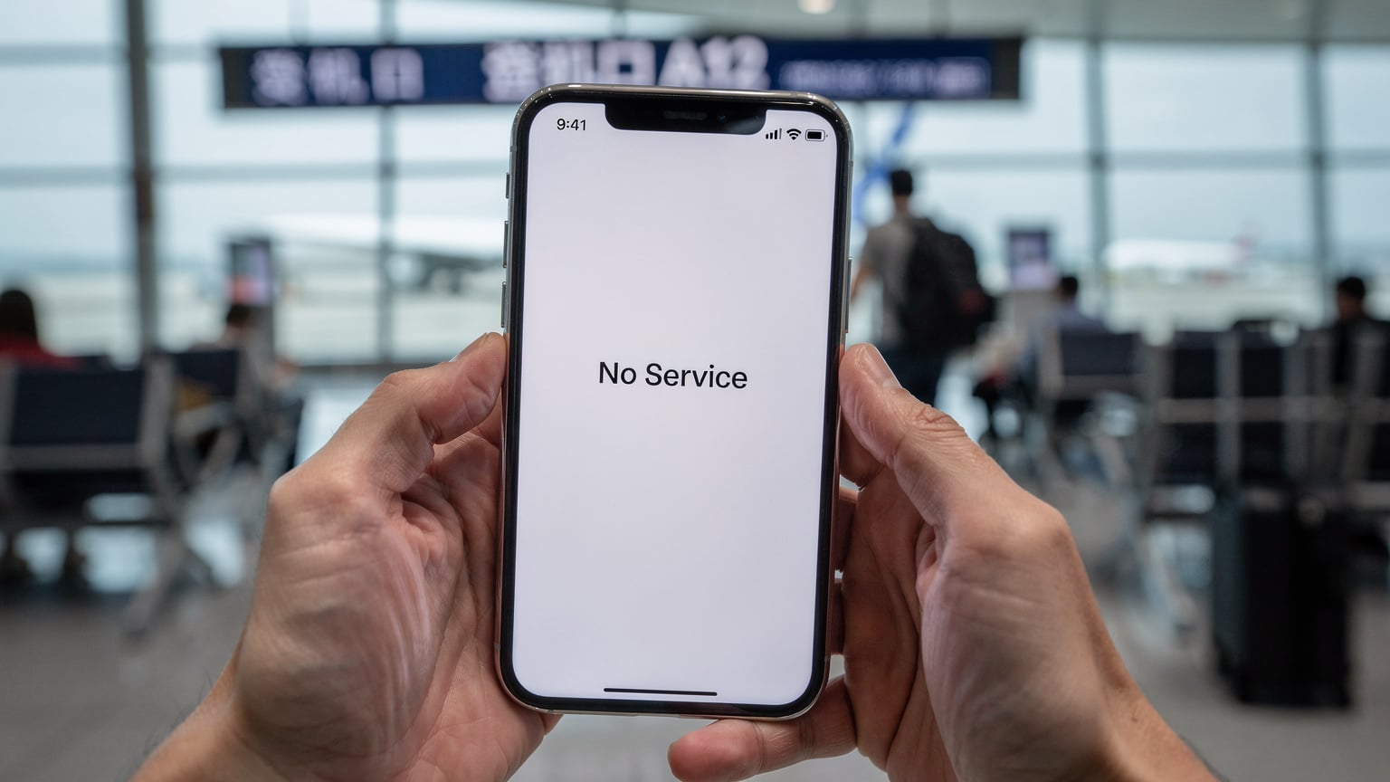 A close-up of a smartphone screen showing a 'No Service' error, held by a worried traveler at a busy airport gate in China, emphasizing a common travel problem.
