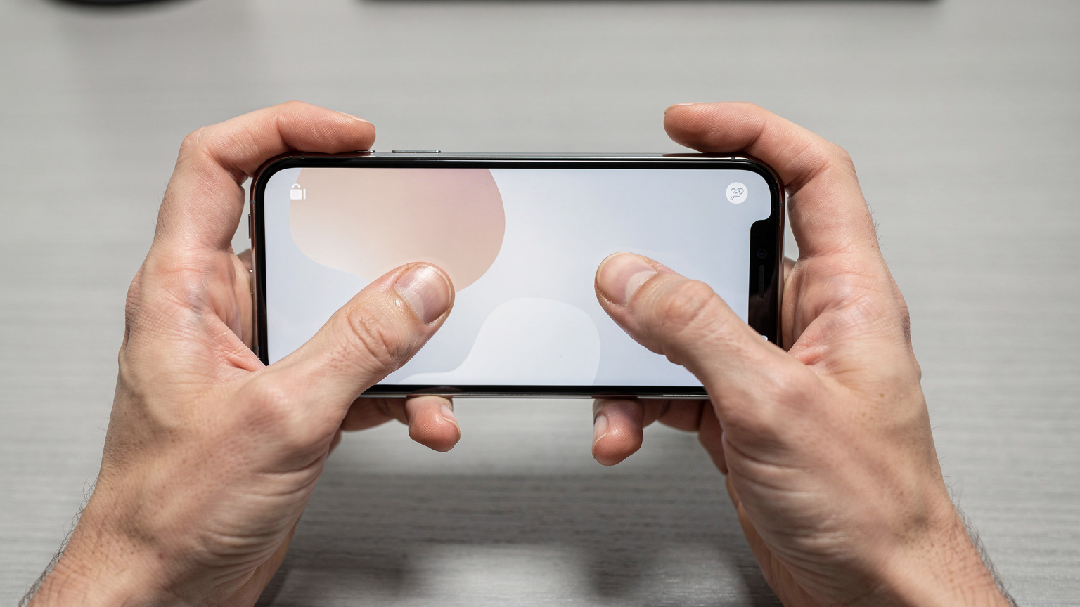 Eine Nahaufnahme zeigt die Hände einer Person, die ein iPhone in der Hand hält und auf dem Bildschirm nach den Einstellungen für die Mobilfunkverbindung sucht.