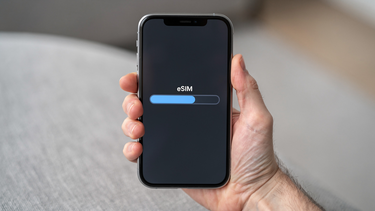 Eine Nahaufnahme einer Hand, die ein Smartphone hält, auf dessen Bildschirm gerade ein eSIM-Profil heruntergeladen wird, mit einem Ladebalken, der den Fortschritt anzeigt.