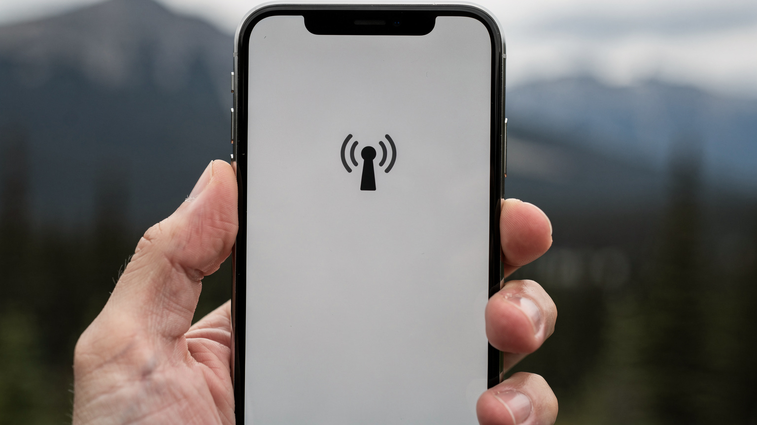 Un écran de smartphone affichant une icône de signal faible ou inexistant, avec un globe terrestre en arrière-plan, symbolisant la perte de connexion internet dans une zone reculée.