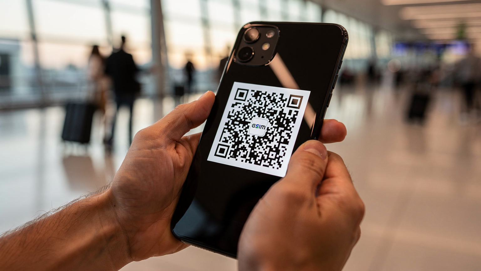 Un viajero activa su eSIM escaneando un código QR en su teléfono móvil, con el fondo desenfocado de una bulliciosa terminal de aeropuerto, mostrando la facilidad y rapidez del proceso.