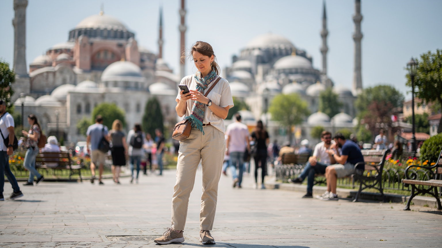 A traveler using their smartphone to navigate Istanbul's historic Sultanahmet Square, surrounded by bustling crowds and iconic architecture, capturing the essence of being connected amidst discovery.