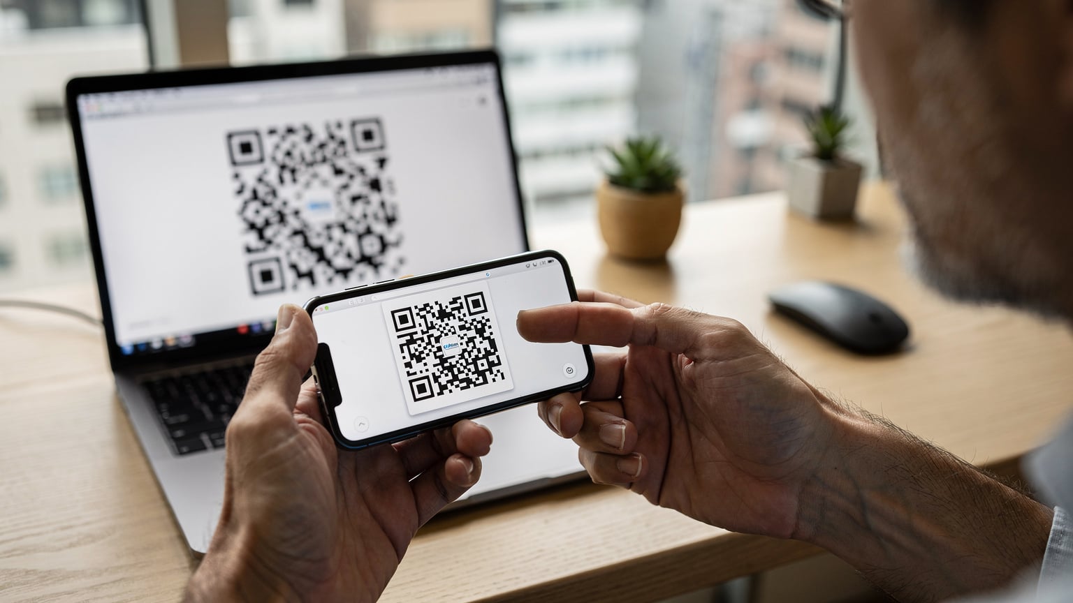 指でCellesim eSIMのQRコードをスマートフォンでスキャンしている日本人男性の手元。