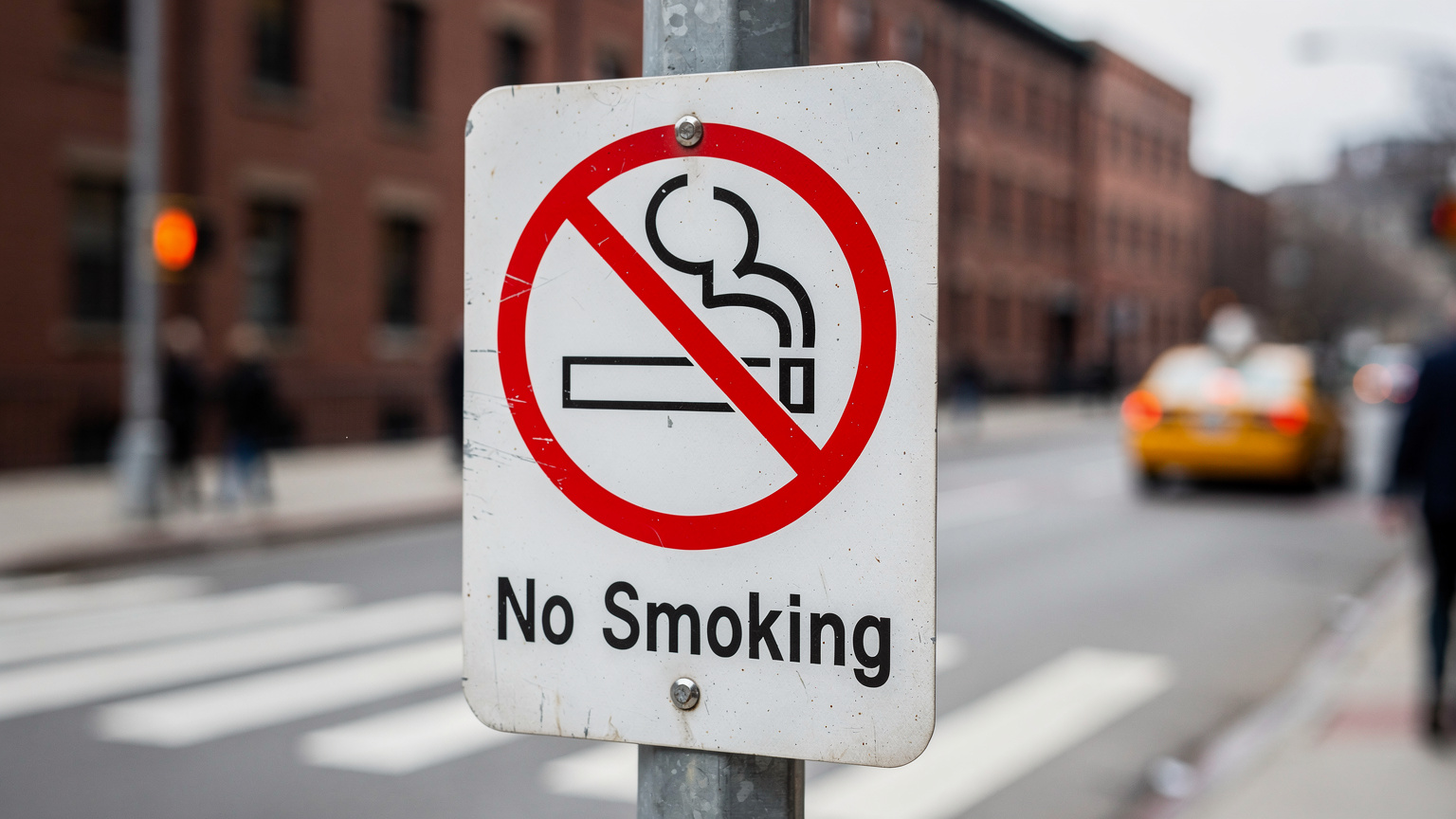 Табличка с надписью "No Smoking" на общественной территории в США, на фоне видно городскую улицу.