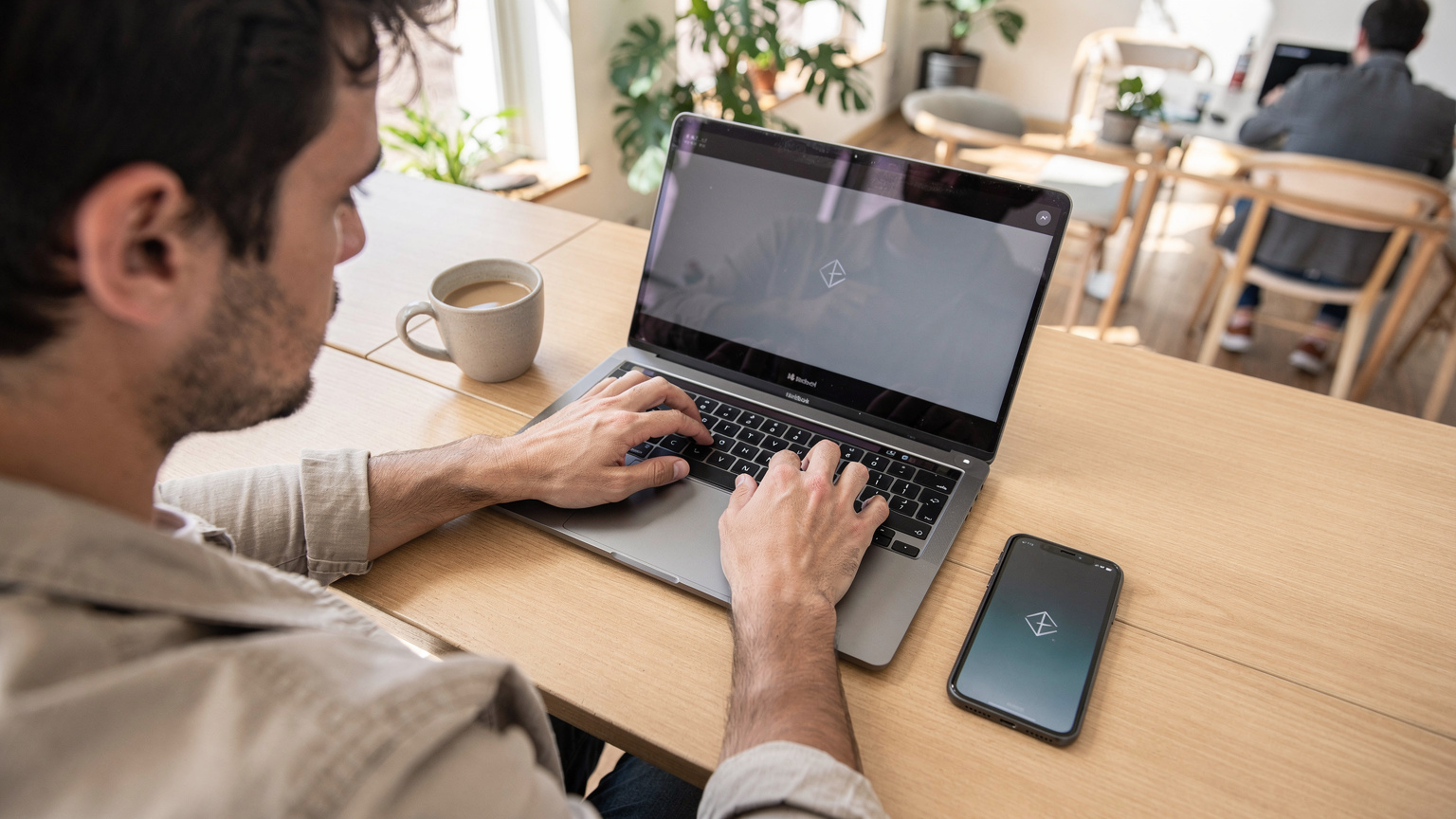 Un nómada digital trabaja en su laptop con una buena taza de café en un espacio de coworking moderno en Buenos Aires, Argentina, con su teléfono mostrando la conexión eSIM.