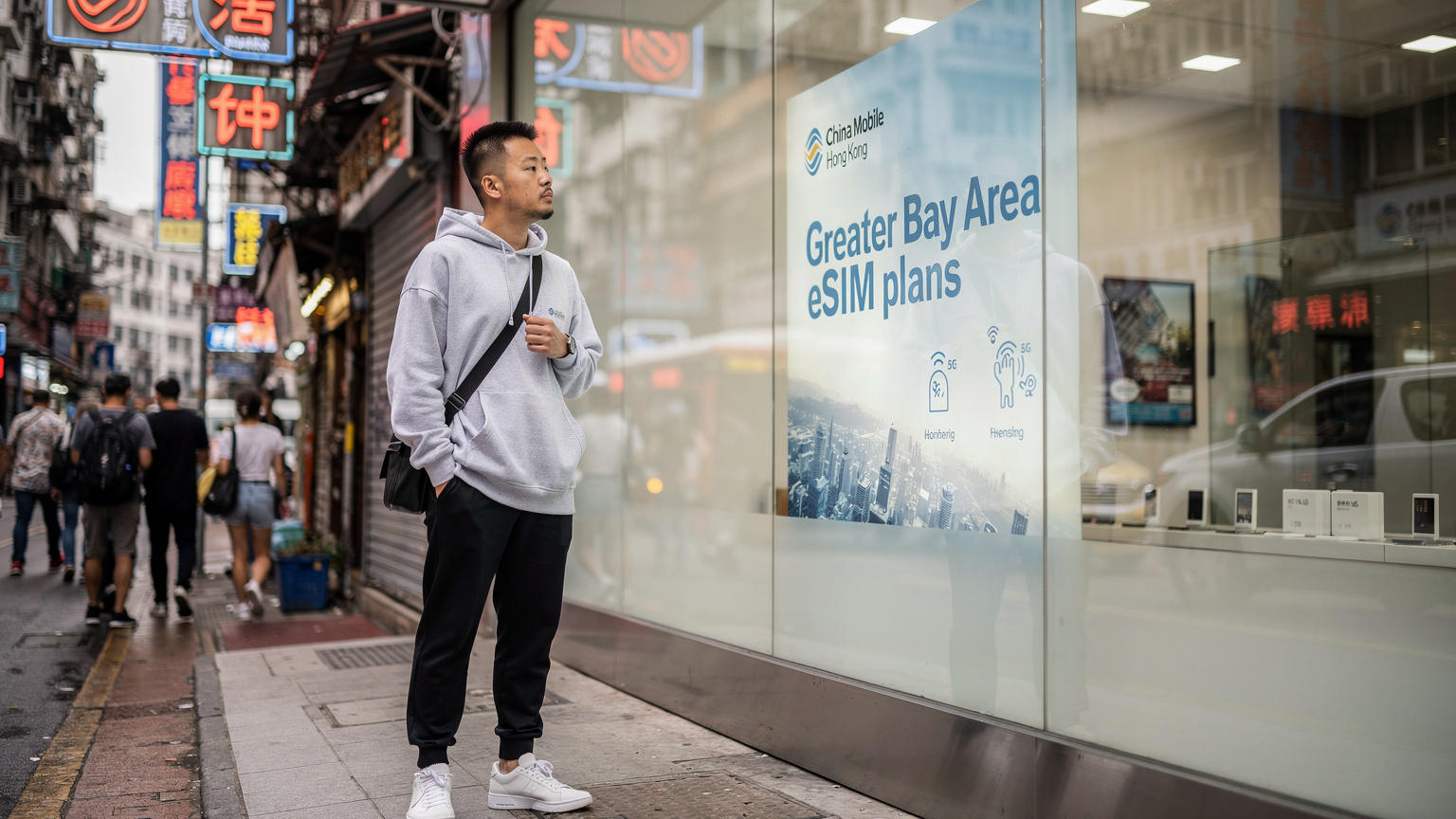 一名身著休閒服的年輕男性在香港街頭的中國移動門店外駐足,研究著櫥窗裡關於大灣區eSIM套餐的廣告。