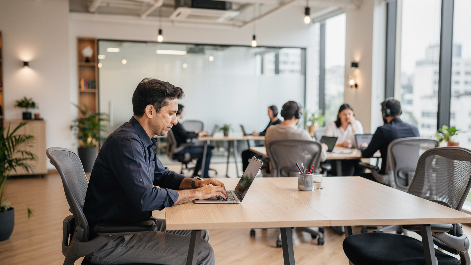 Ein Reisender, der an einem Laptop in einem modernen Co-Working Space in São Paulo arbeitet, umgeben von anderen digitalen Nomaden, die konzentriert sind.