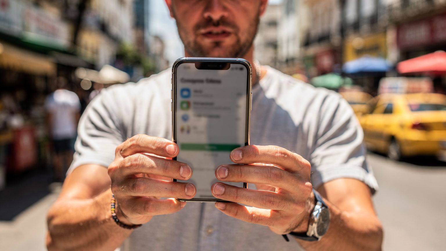 Ein Reisender zeigt seine Hände, die ein Smartphone halten, auf dem eine Notfallkontaktliste und die Cellesim-App sichtbar sind, während er sich in einer geschäftigen Straße in Rio de Janeiro befindet.
