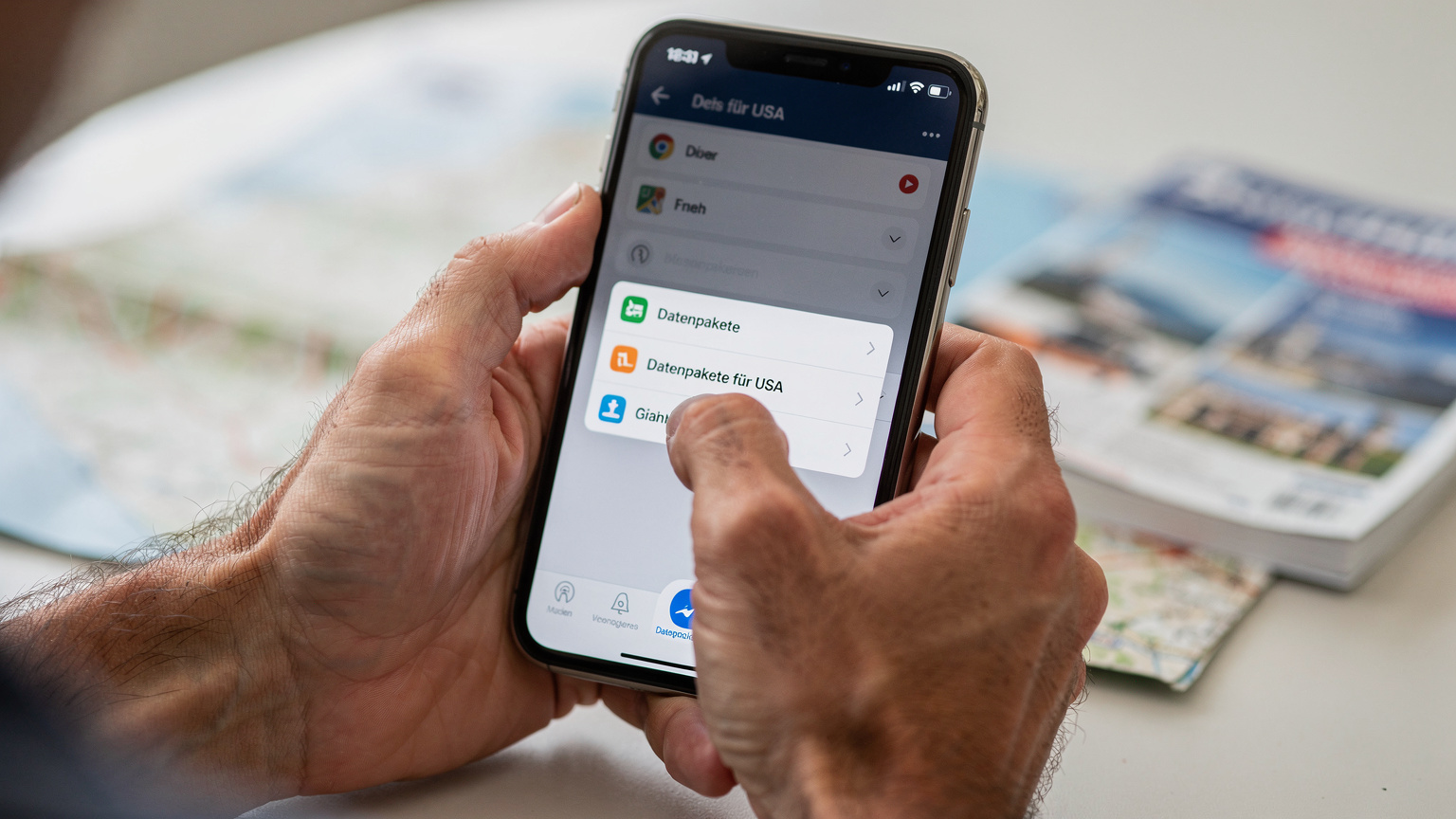 Nahaufnahme der Hände einer Person, die auf einem Smartphone durch eine eSIM-App scrollt, mit dem Fokus auf die Interaktion und die Auswahl eines Datenpakets für eine Auslandsreise. Der Hintergrund ist leicht verschwommen und zeigt eine Reisethematik.
