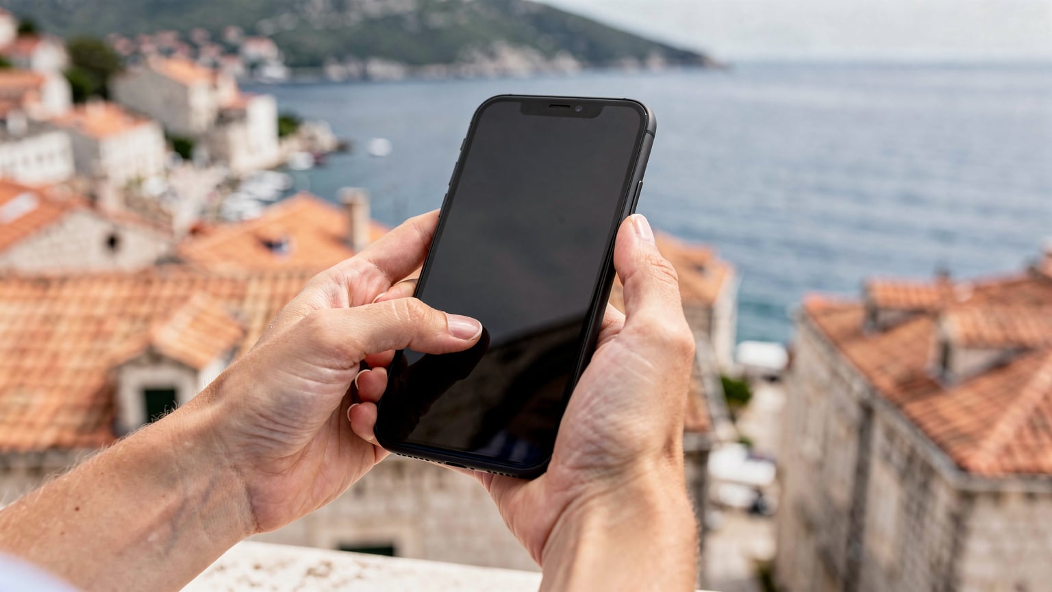 Nahaufnahme einer Hand, die auf einem Smartphone-Bildschirm eine eSIM-Installationsanleitung verfolgt, mit einer kroatischen Küstenlandschaft im verschwommenen Hintergrund.