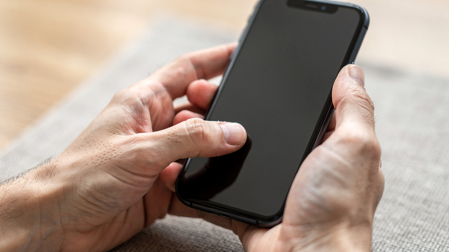 Close-up on human hands holding a smartphone, with one thumb gently swiping up to reveal the control center, indicating a check of network settings.