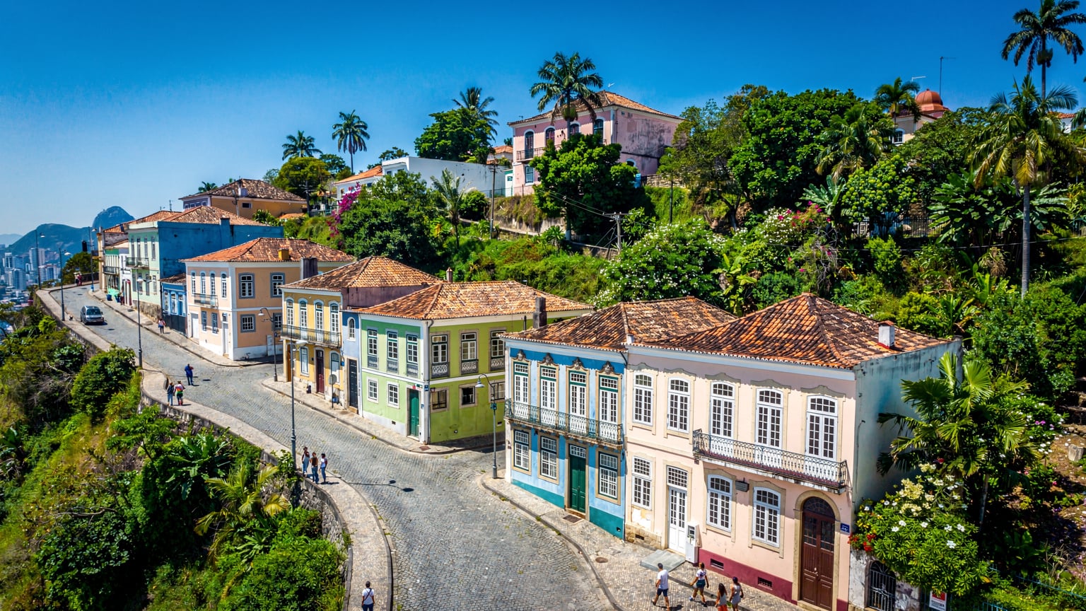 Vue aérienne du quartier de Santa Teresa à Rio de Janeiro, avec ses rues sinueuses et ses maisons colorées, sous un ciel bleu clair, un environnement stimulant la connectivité.