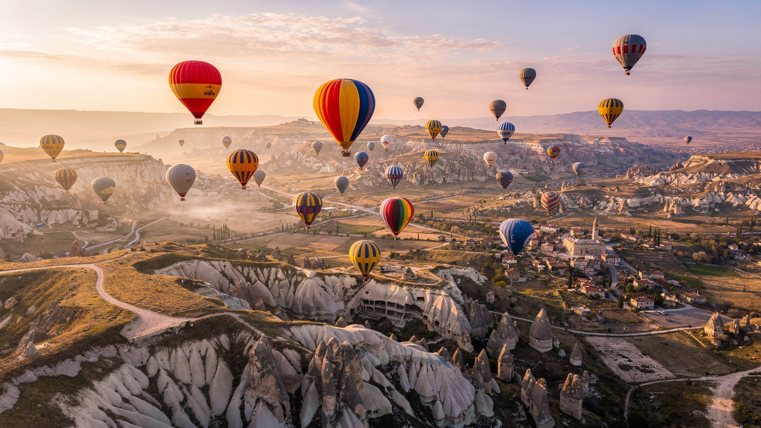 Une vue aérienne spectaculaire de la Cappadoce au lever du soleil, avec des montgolfières colorées s'élevant dans le ciel, capturant la magie de la Turquie. La scène est paisible et majestueuse.