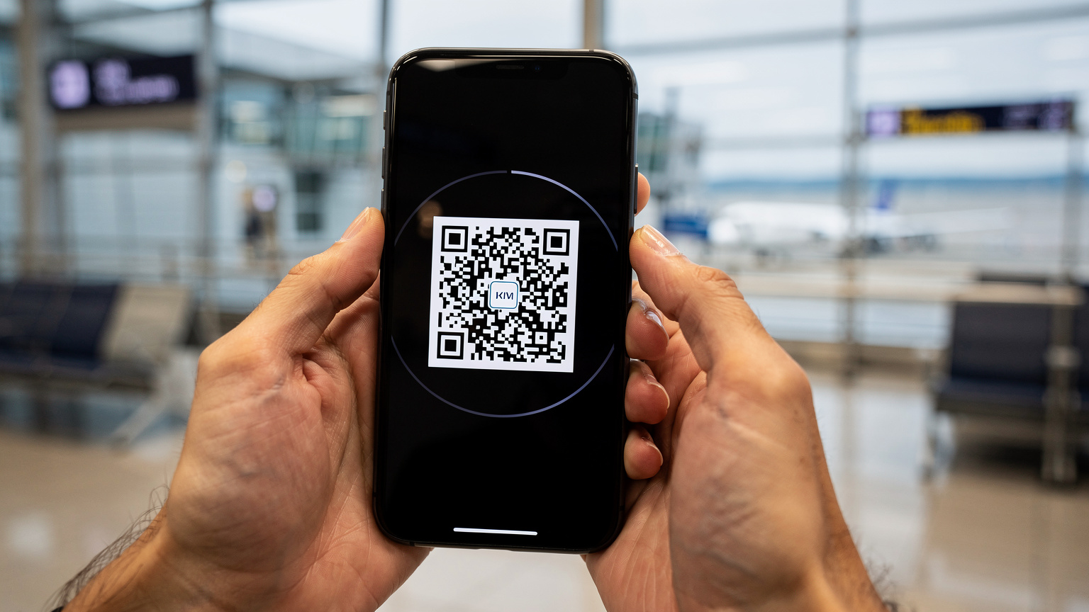 Een close-up van een reiziger die zijn smartphone vasthoudt met het scherm aan, terwijl hij een QR-code scant voor eSIM-installatie in een rustige hoek van Kansai International Airport (KIX).