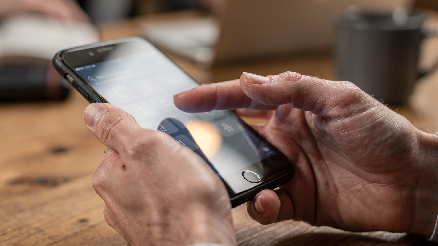 Close-up of hands holding a smartphone, with one finger pointing to a network settings menu, illustrating a troubleshooting scenario.
