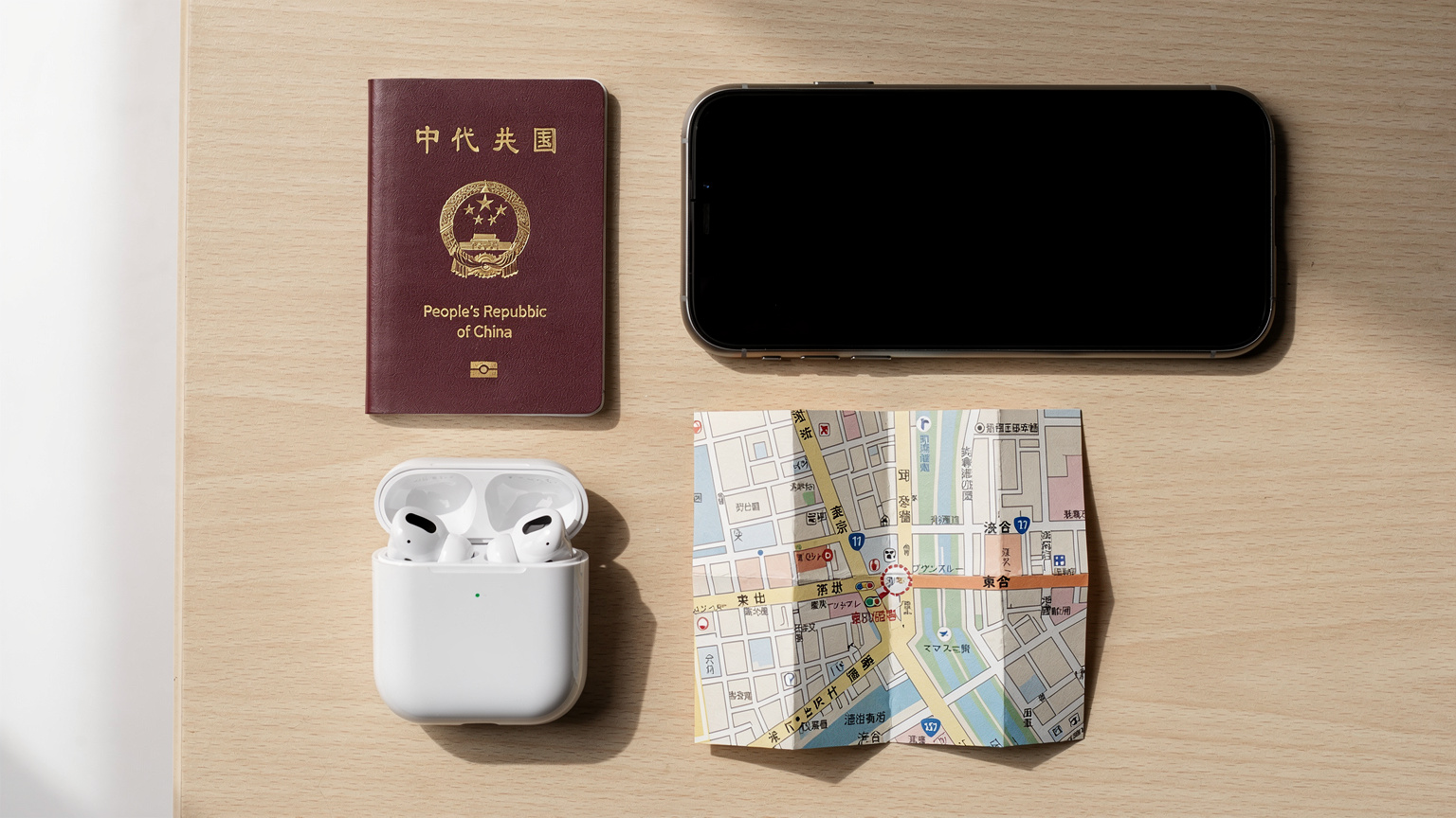 一張護照、一部智能手機、一副耳機和一張地圖平鋪在桌面上,整齊排列,營造出旅行前的準備氛圍。