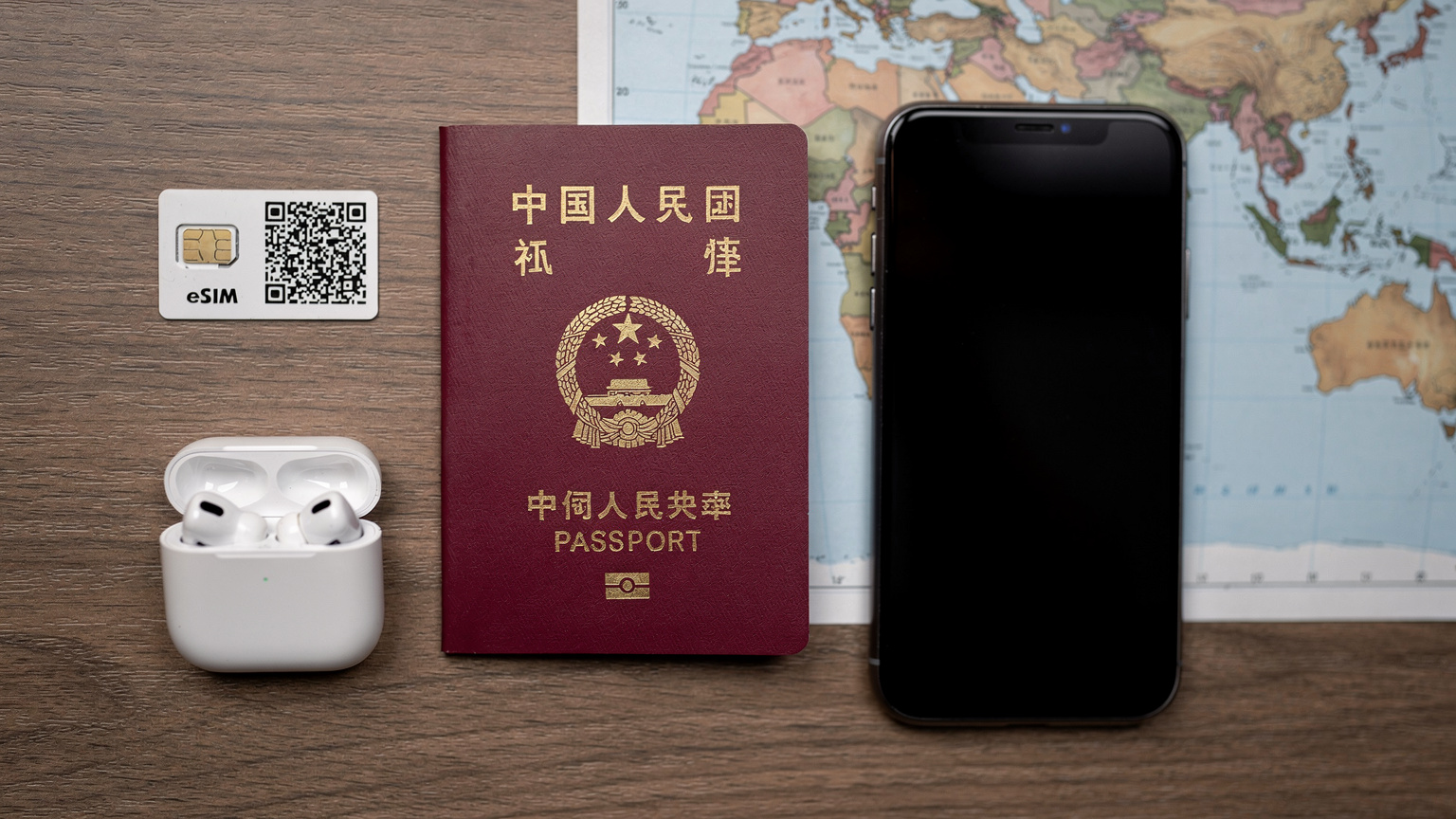 一張整齊擺放的旅行用品俯視圖,包括一本中國護照、一部智能手機、無線耳機和一張eSIM激活卡片,背景是世界地圖。