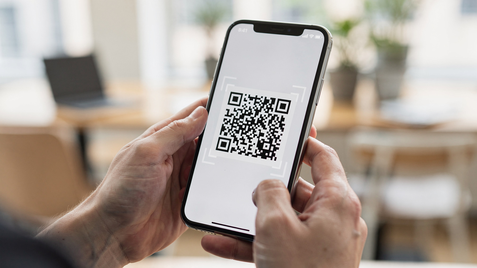 Une personne scannant un QR code eSIM avec son smartphone, dans un espace moderne et bien éclairé.