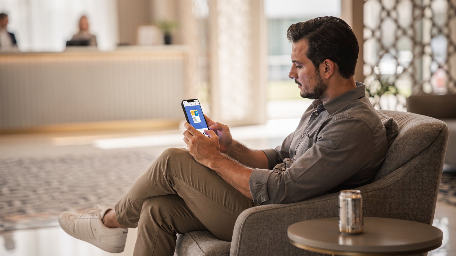 Bir otel lobisinde, elinde telefon tutan bir gezgin, ekranında Cellesim uygulamasındaki eSIM kurulum ekranını inceliyor.
