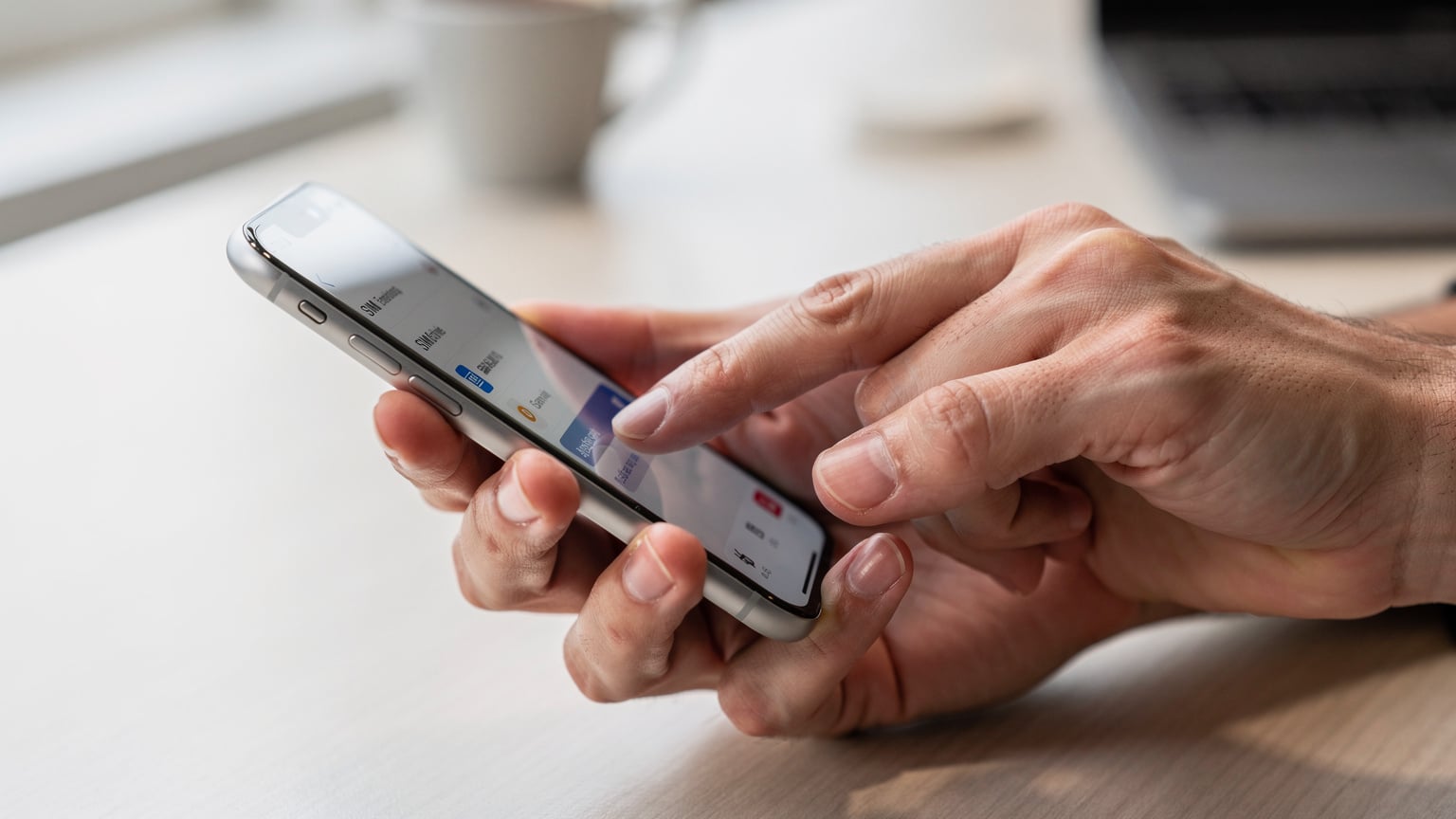 Een close-up van een hand die een smartphone vasthoudt, waarbij de vingers over het scherm vegen om een eSIM-profiel te selecteren in de instellingen, met een lichte onscherpte van de achtergrond.