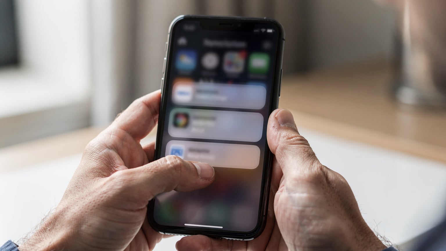 A close-up of a traveler's hands interacting with an iPhone, navigating through the 'Settings' menu to locate their eSIM details.
