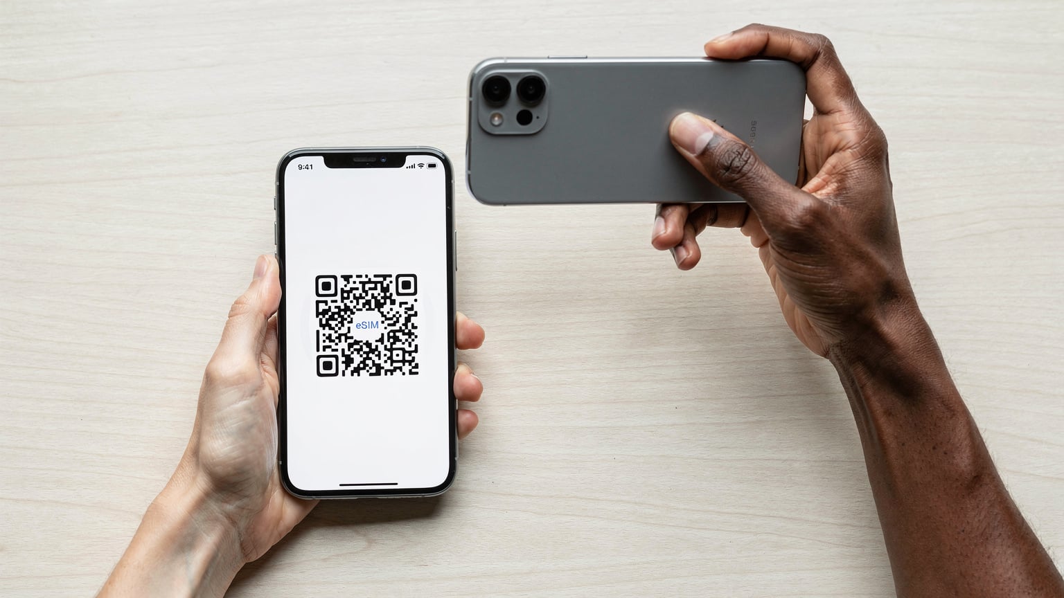 Una mano sostiene un smartphone mostrando un código QR en la pantalla, mientras otra mano se prepara para escanearlo con otro teléfono, simbolizando la activación de la eSIM.